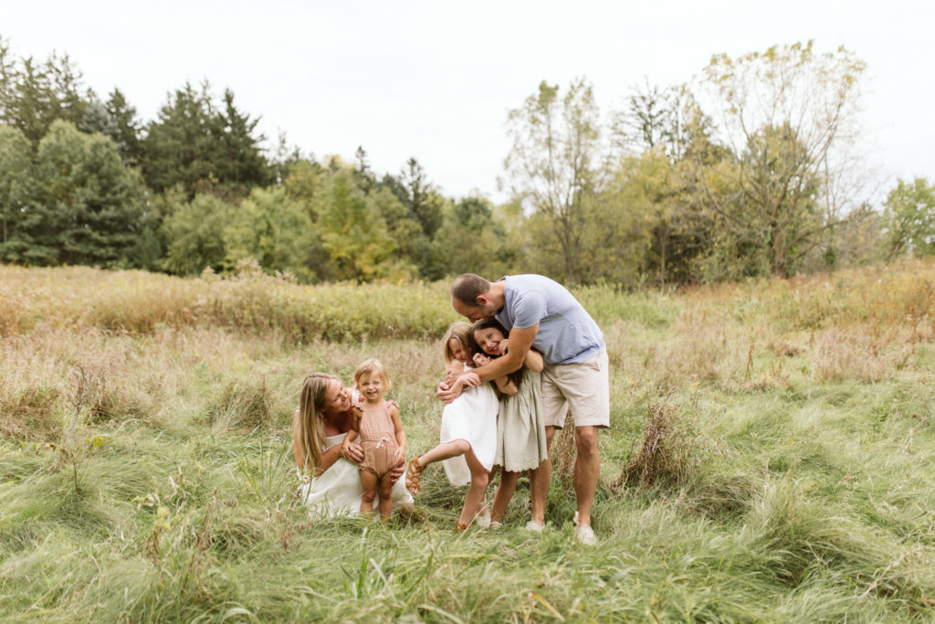 family playing and laughing in a green field